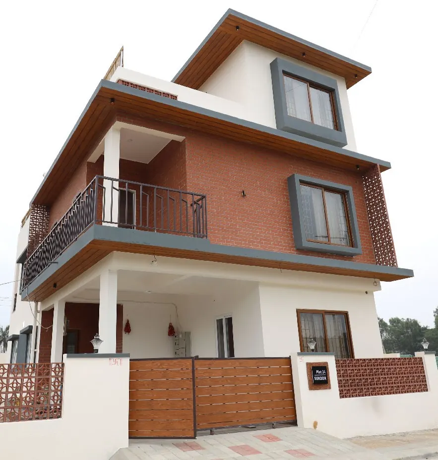 Completed three-storey residential house with brick facade and wooden gate built by Sri Siddhi Infra and Interiors